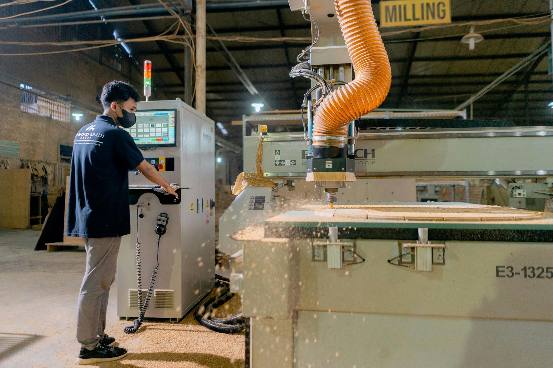 Worker operating a large industrial milling machine in a factory workshop