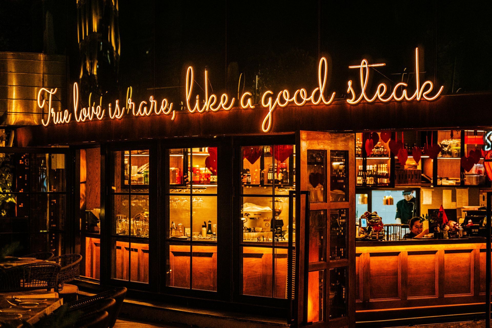 Steakhouse storefront at night with glowing neon sign and warm-lit windows