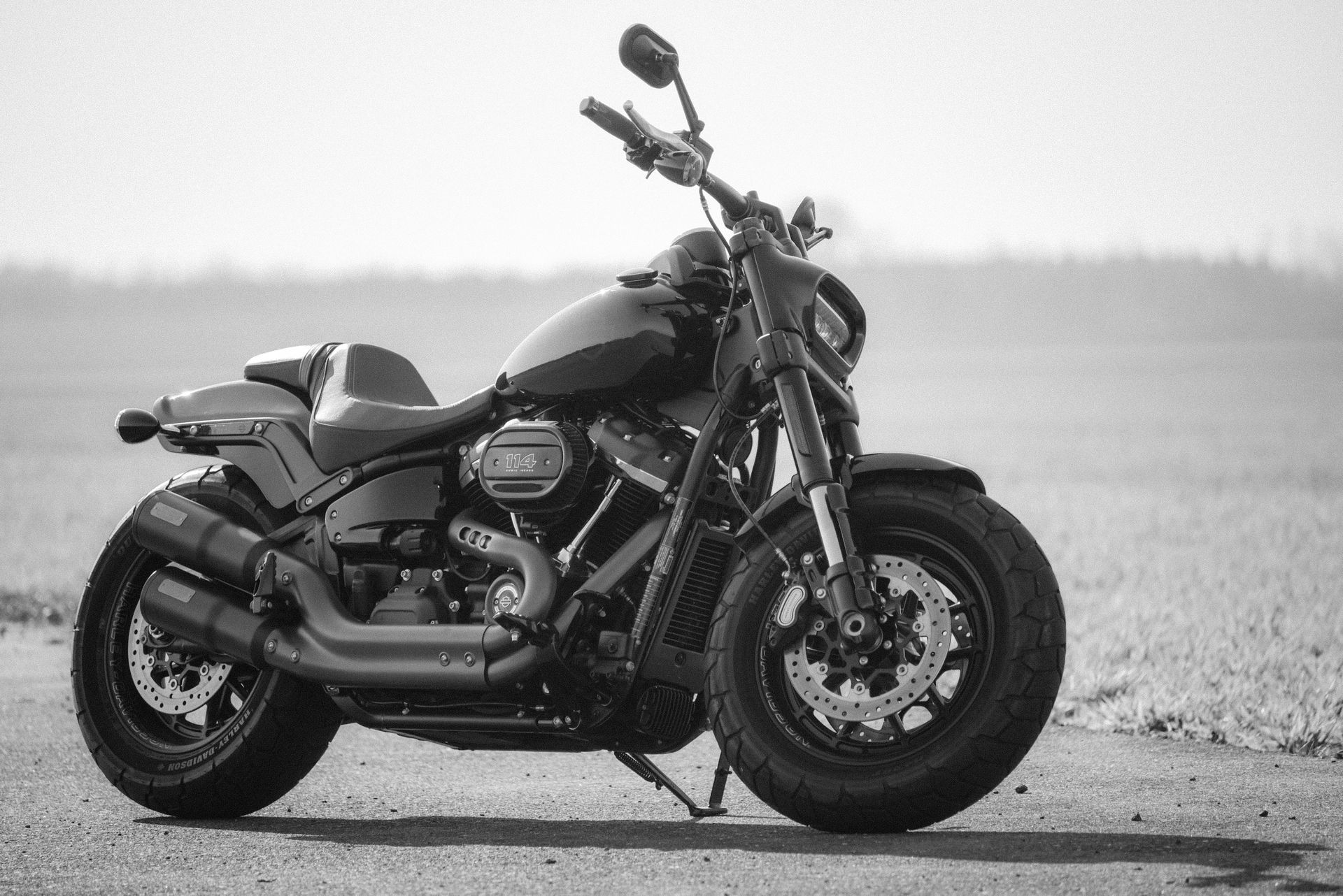 Black motorcycle parked on a road with a blurred field in the background