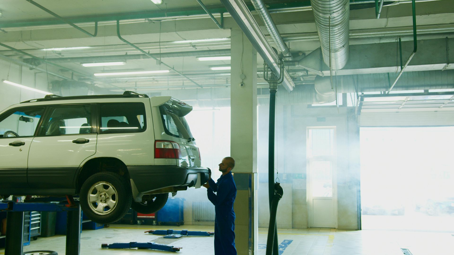 Mechanic inspecting a lifted SUV in an auto repair garage