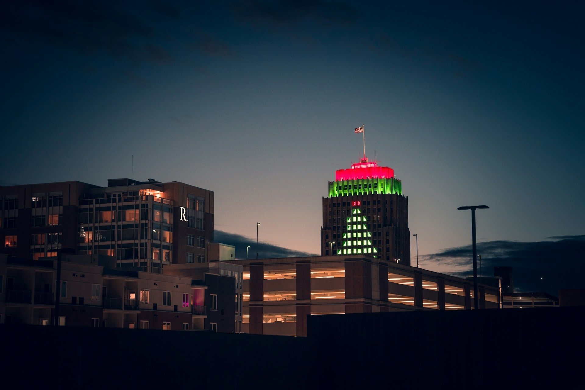 Night skyline with a lit tower topped in red and green against a dark sky