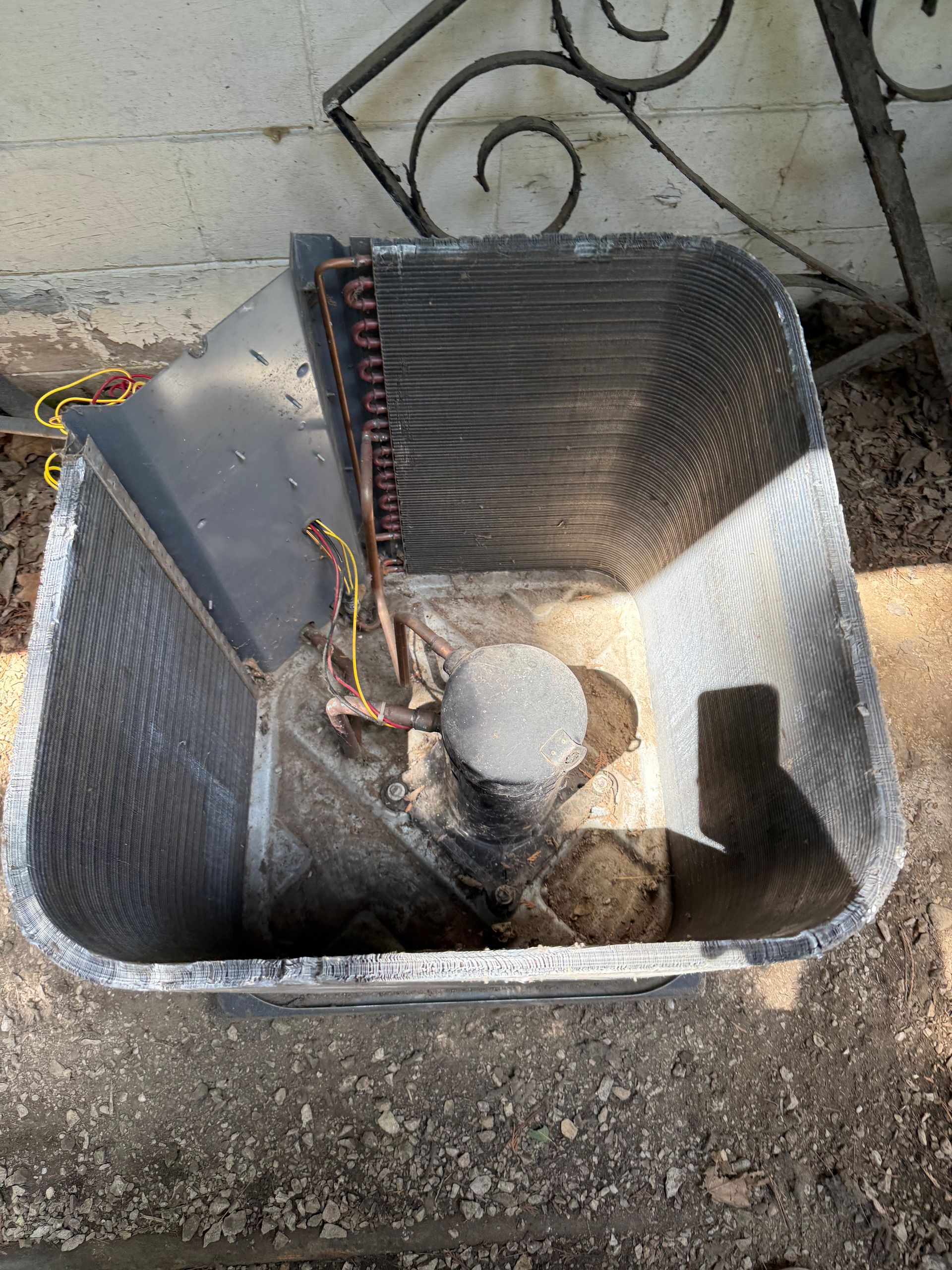 An overhead view of the open casing of an air conditioner unit, showing the internal coils and compressor.