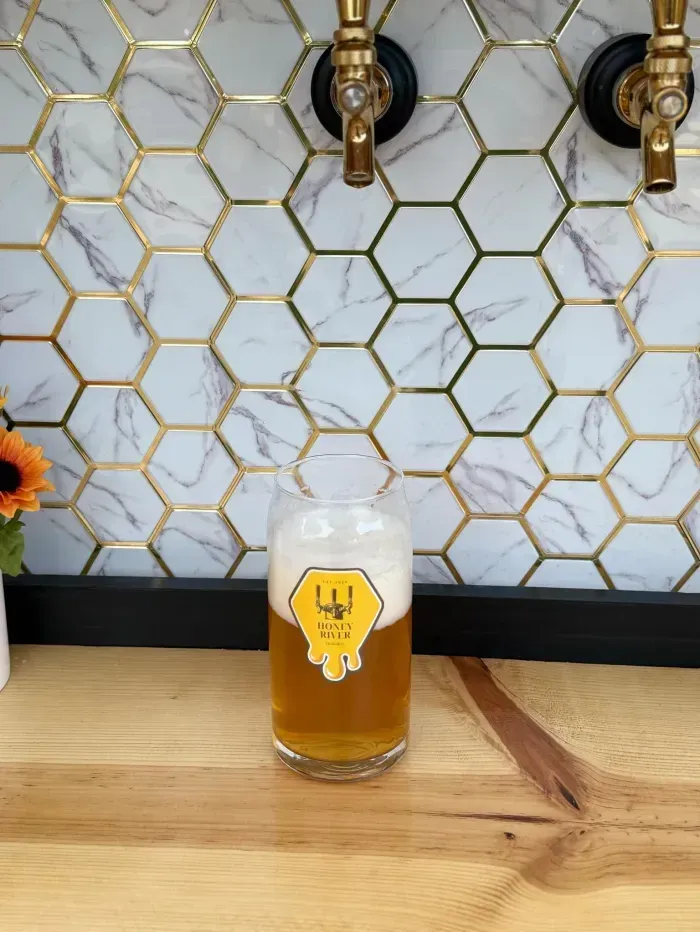 Beer being poured from a tap into a glass, with a honeycomb tile background.
