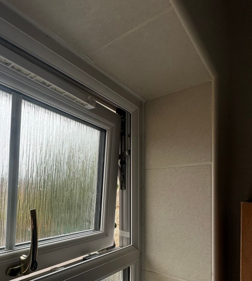 White window with failed, partially open. Beige wall and trim in a bright room.