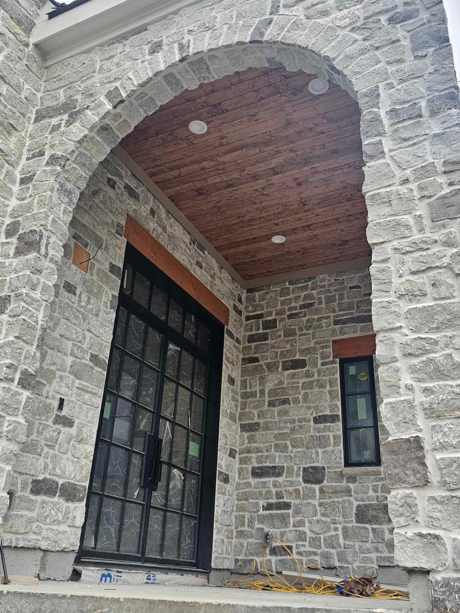A stone building with a black door and a wooden ceiling.