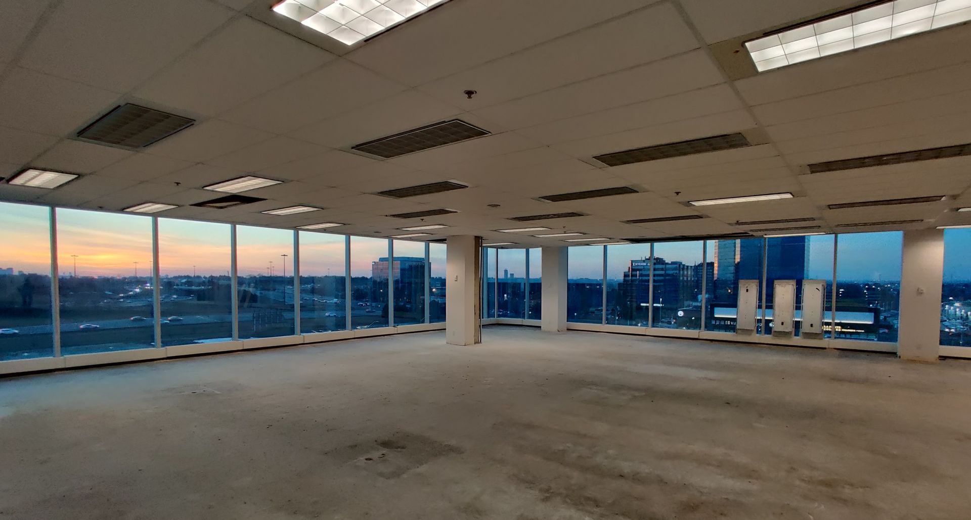 An empty office building with a lot of windows and a view of the city.