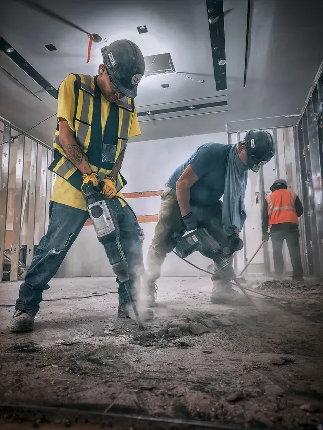 A couple of construction workers are working on a building.