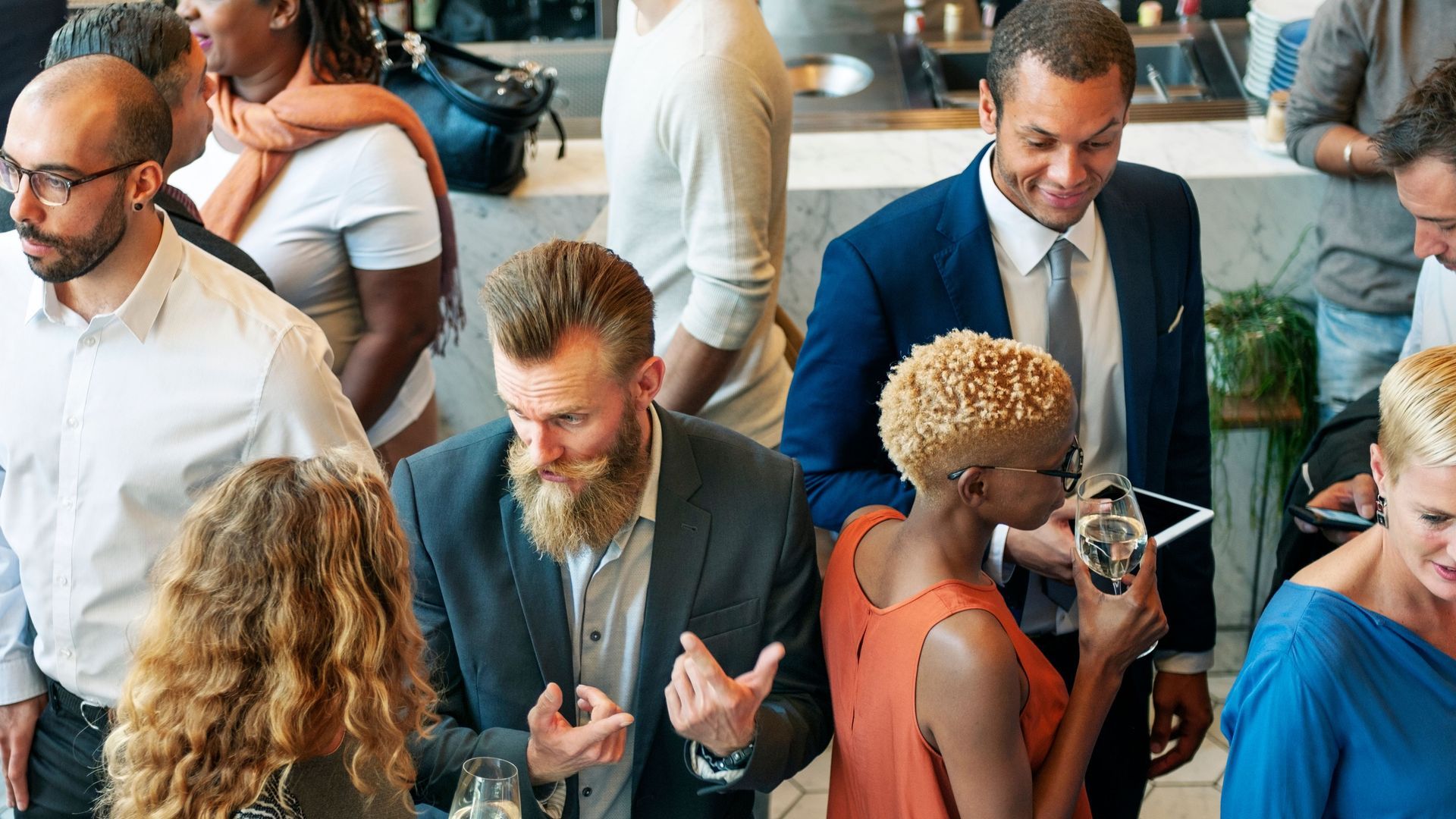 A group of people are standing in a room talking to each other.