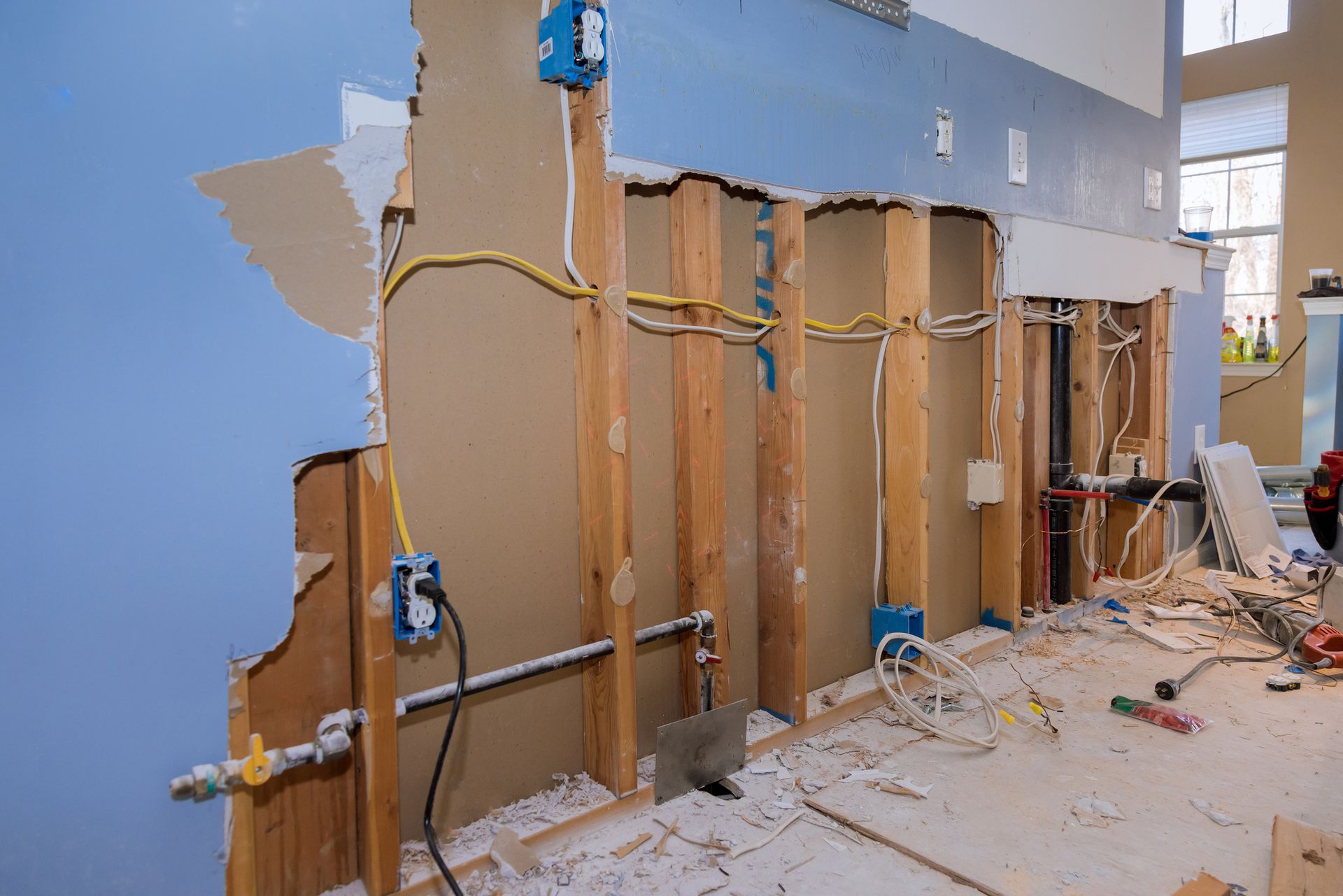 Interior wall under construction with exposed studs, wiring, and blue paint.