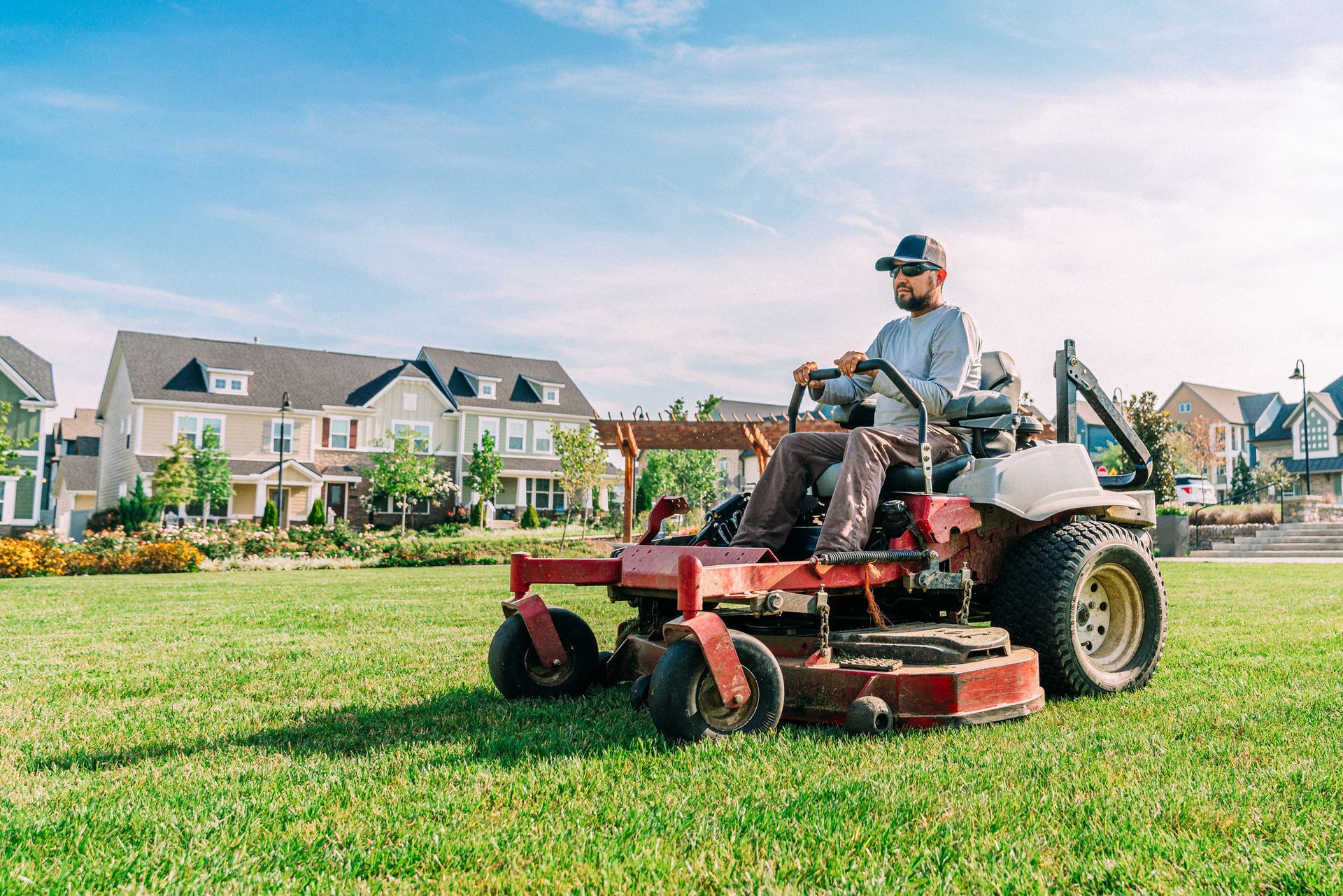 Person on a red riding lawn mower cutting grass in a residential yard. 
