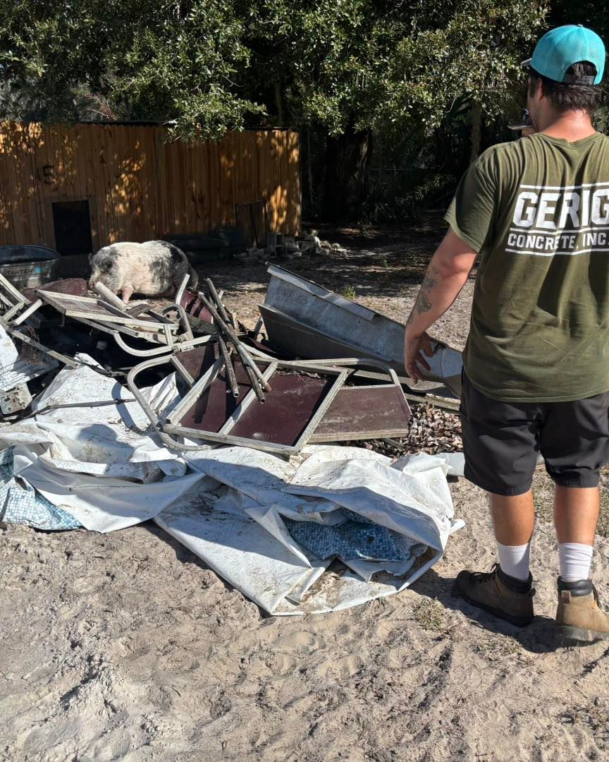 Man in green shirt observes debris pile. 