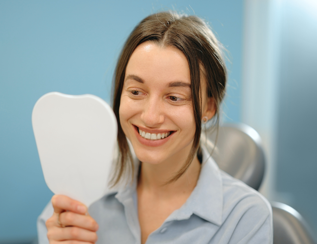 Woman smiling while holding a hand mirror