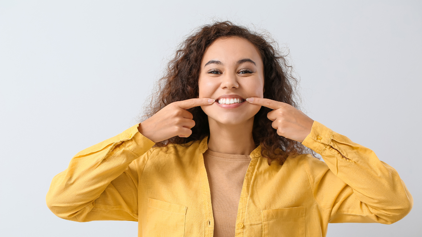 Woman pointing to her teeth and smiling