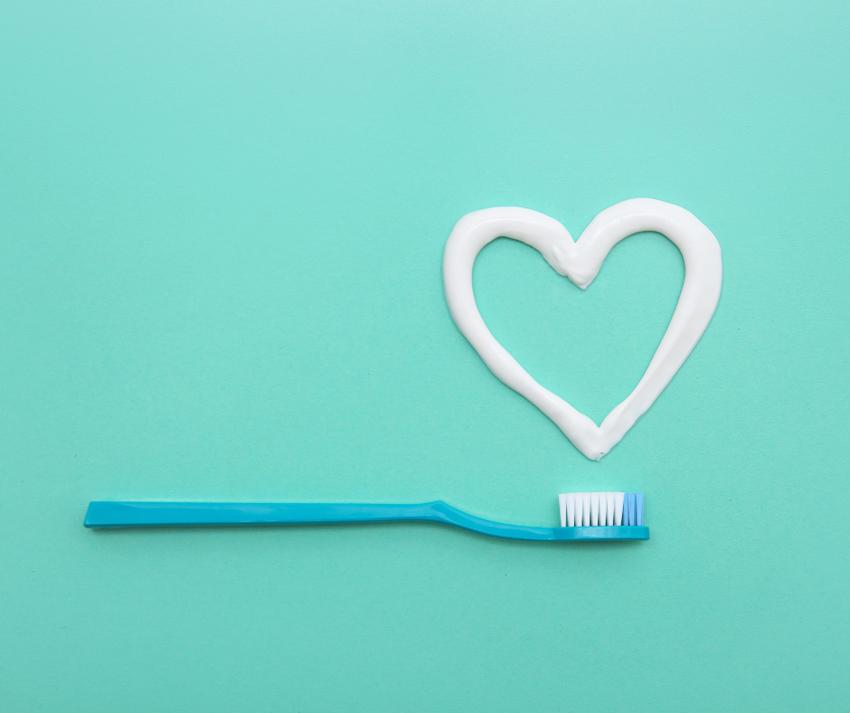 toothpaste formed in the shape of a heart with blue toothbrush underneath