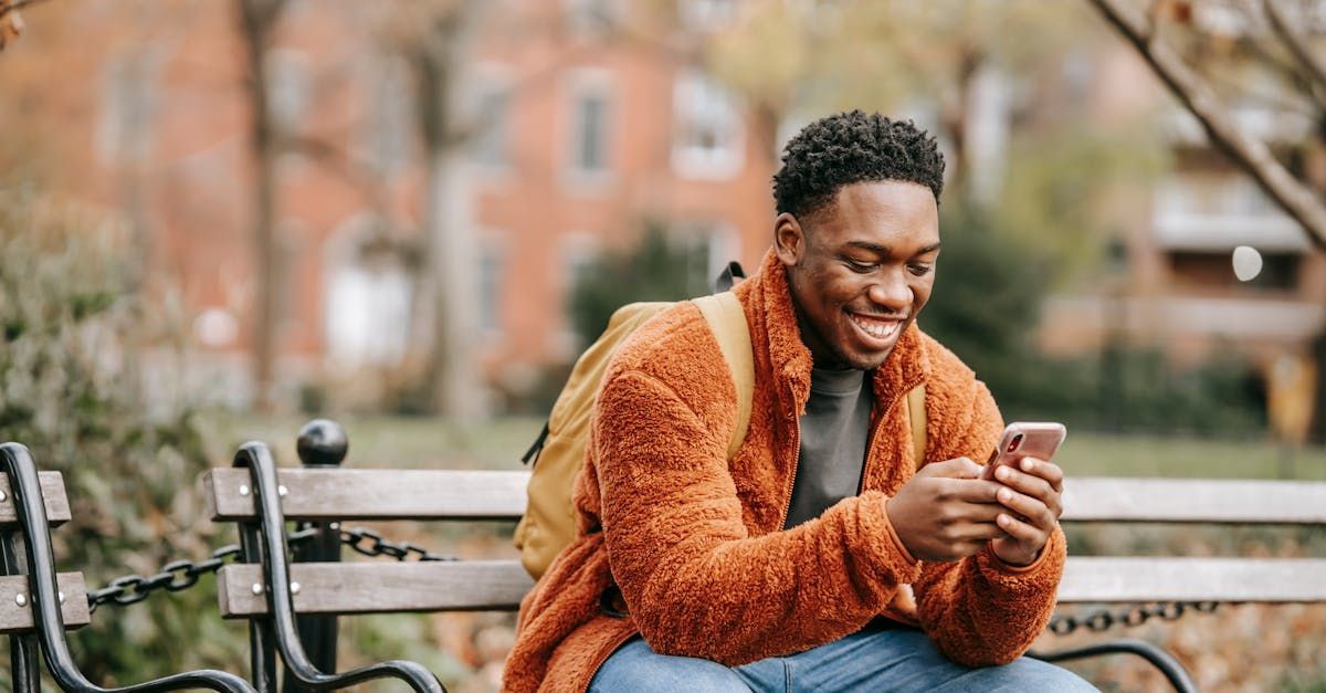 man using phone while sitting on bench