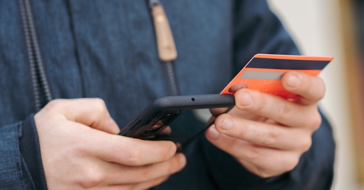 man holding a credit card while looking through the phone