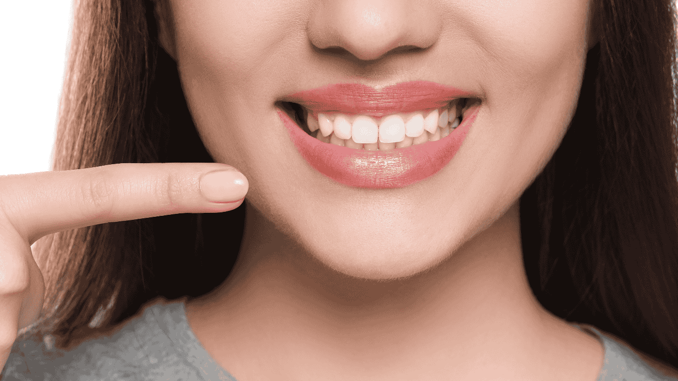 woman smiling, pointing to her pearly whites