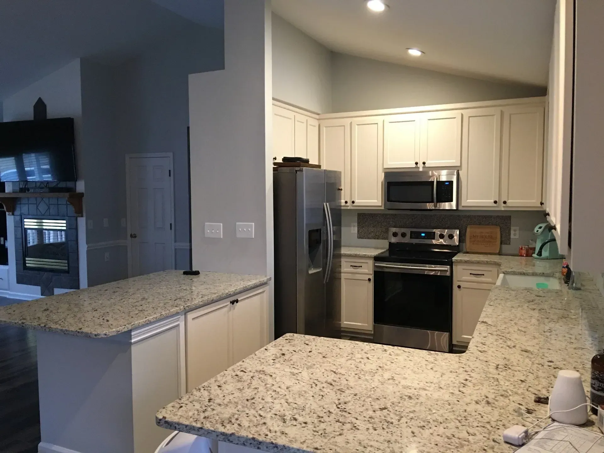 A kitchen with granite counter tops , stainless steel appliances , and white cabinets.