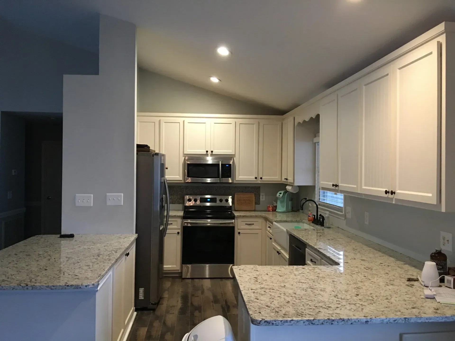 A kitchen with white cabinets , granite counter tops , stainless steel appliances and a stove.