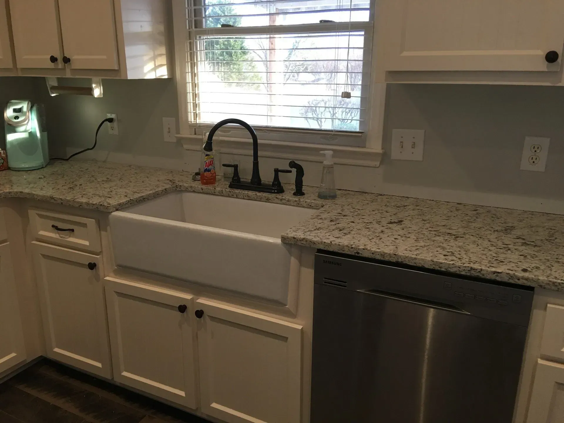 A kitchen with a white sink , stainless steel dishwasher , and granite counter tops.