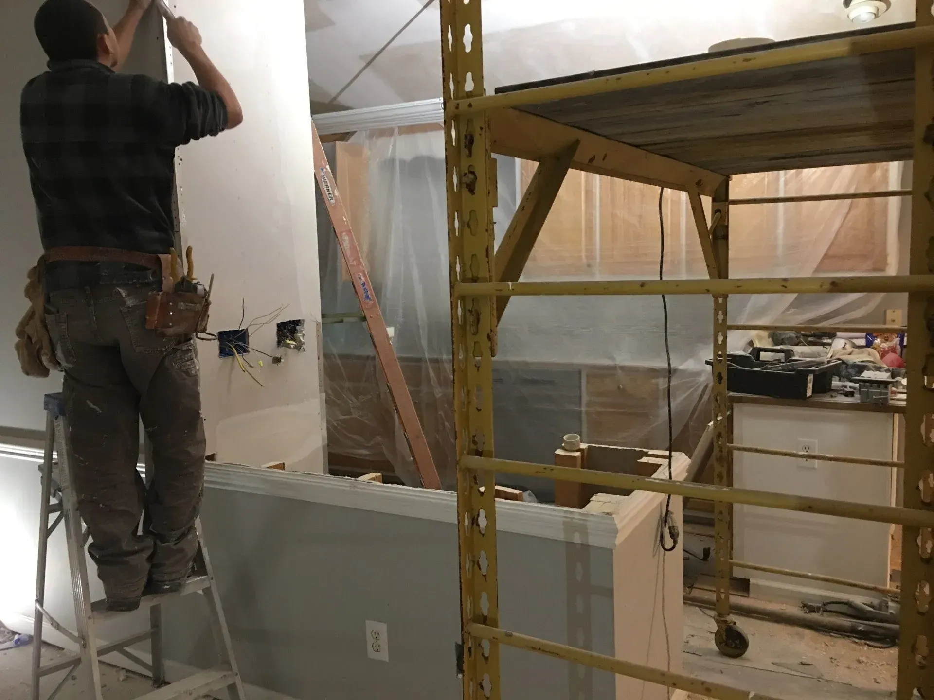 A man is standing on a ladder in a room.