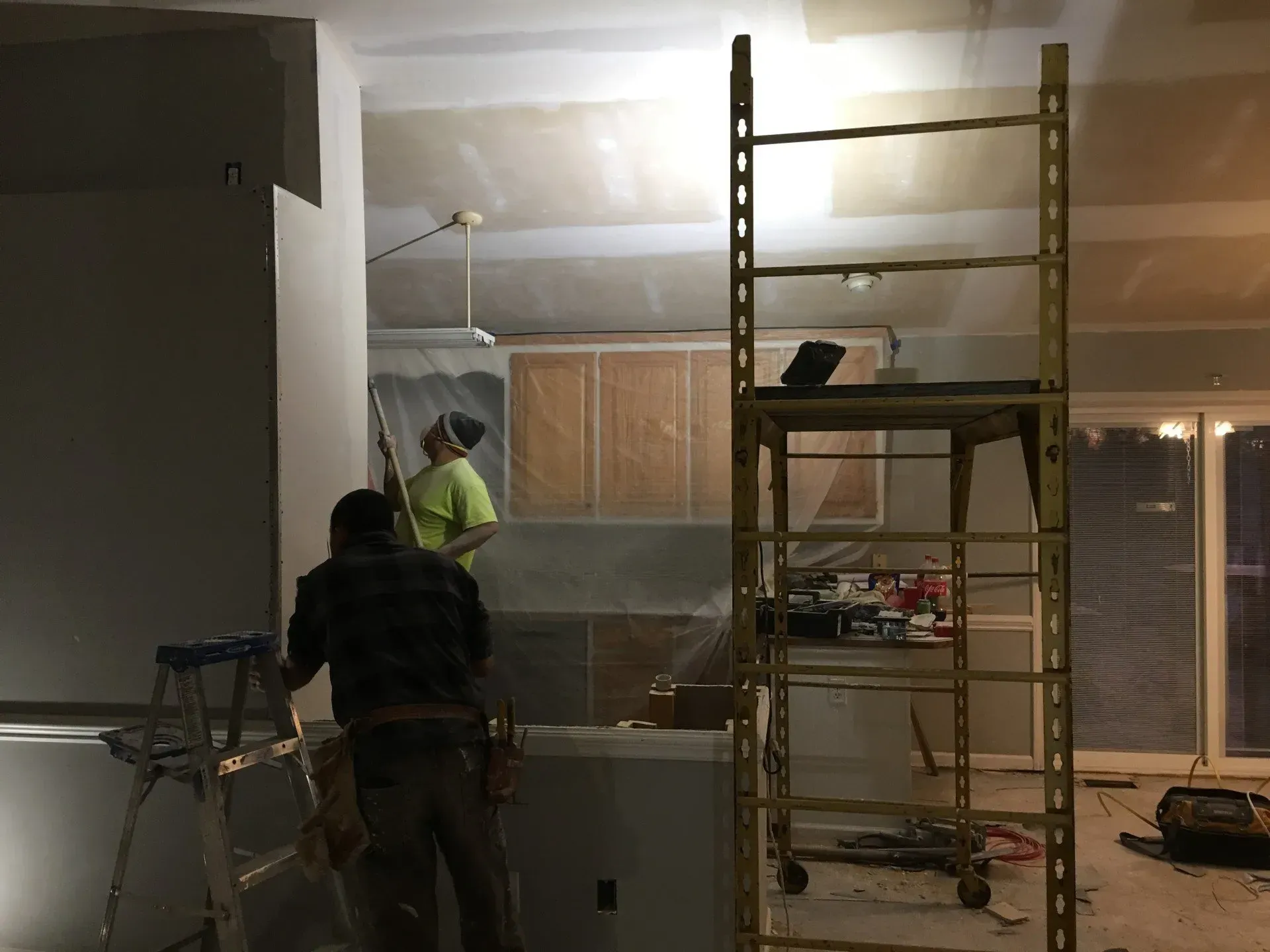 Two men are working on a scaffolding in a room.