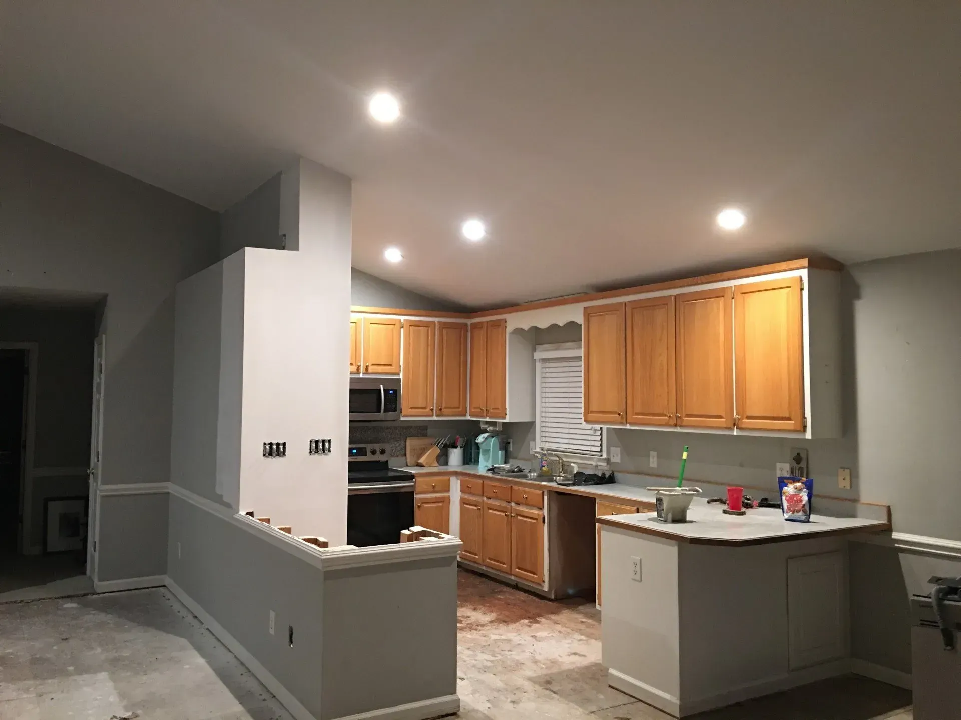 A kitchen with wooden cabinets and white counter tops is being remodeled.