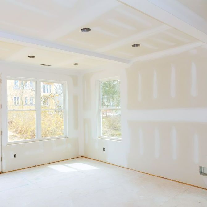 An empty room with drywall on the walls and windows.