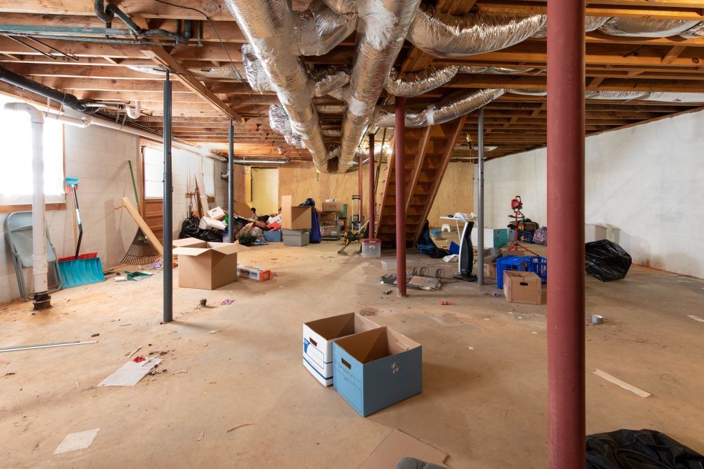 An empty basement with boxes and pipes on the floor.