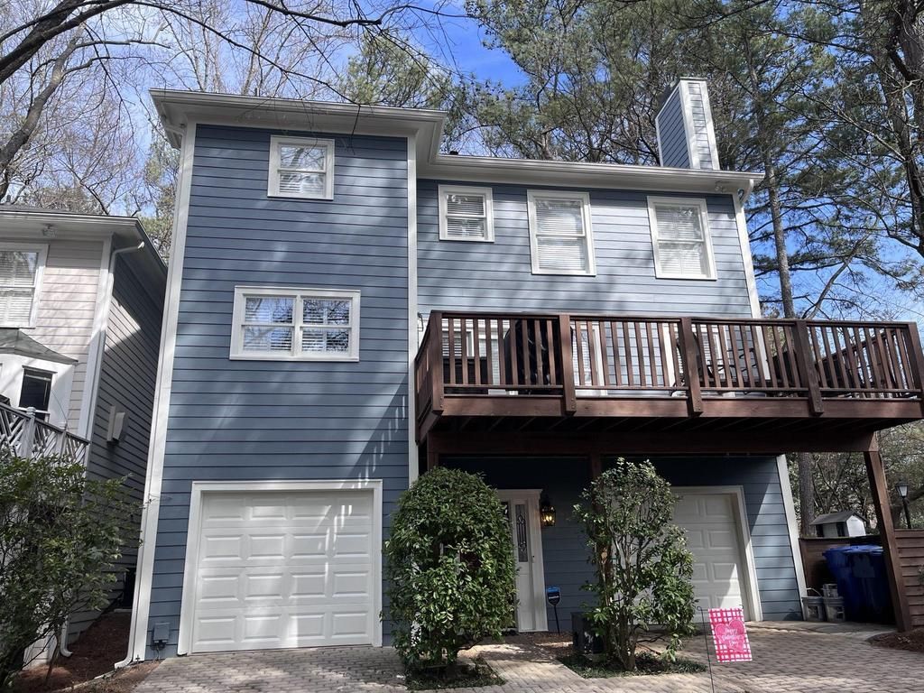 A blue house with a white garage door and a wooden deck.