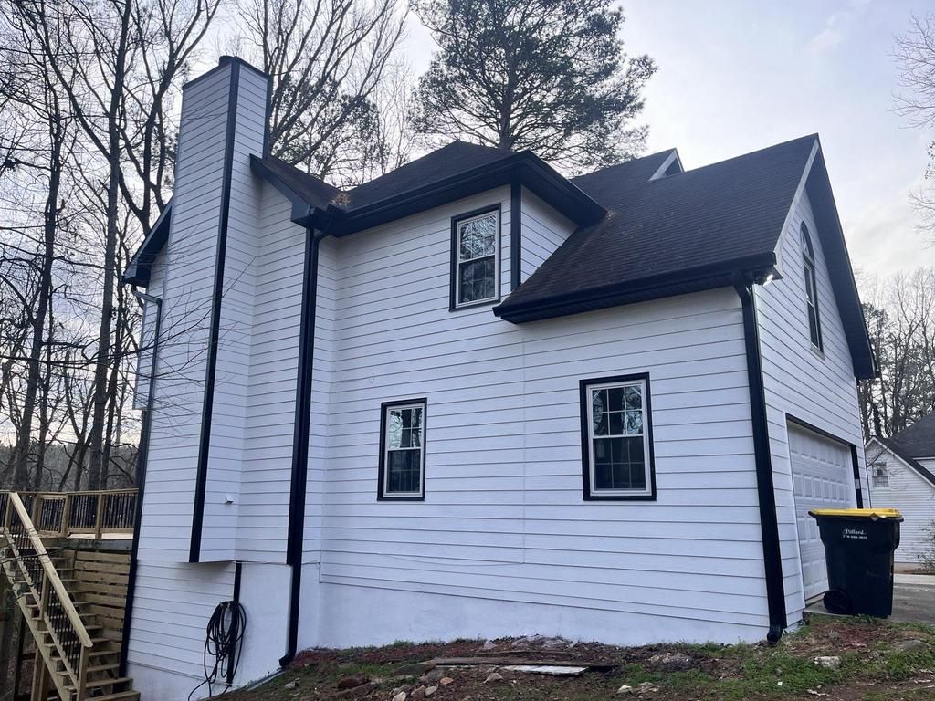 A white house with a black roof and a chimney.