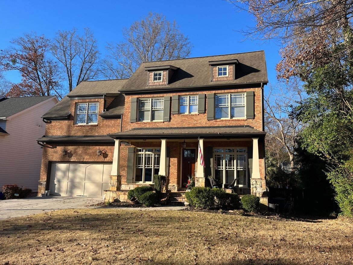 A large brick house with a lot of windows and a roof that has been newly painted.