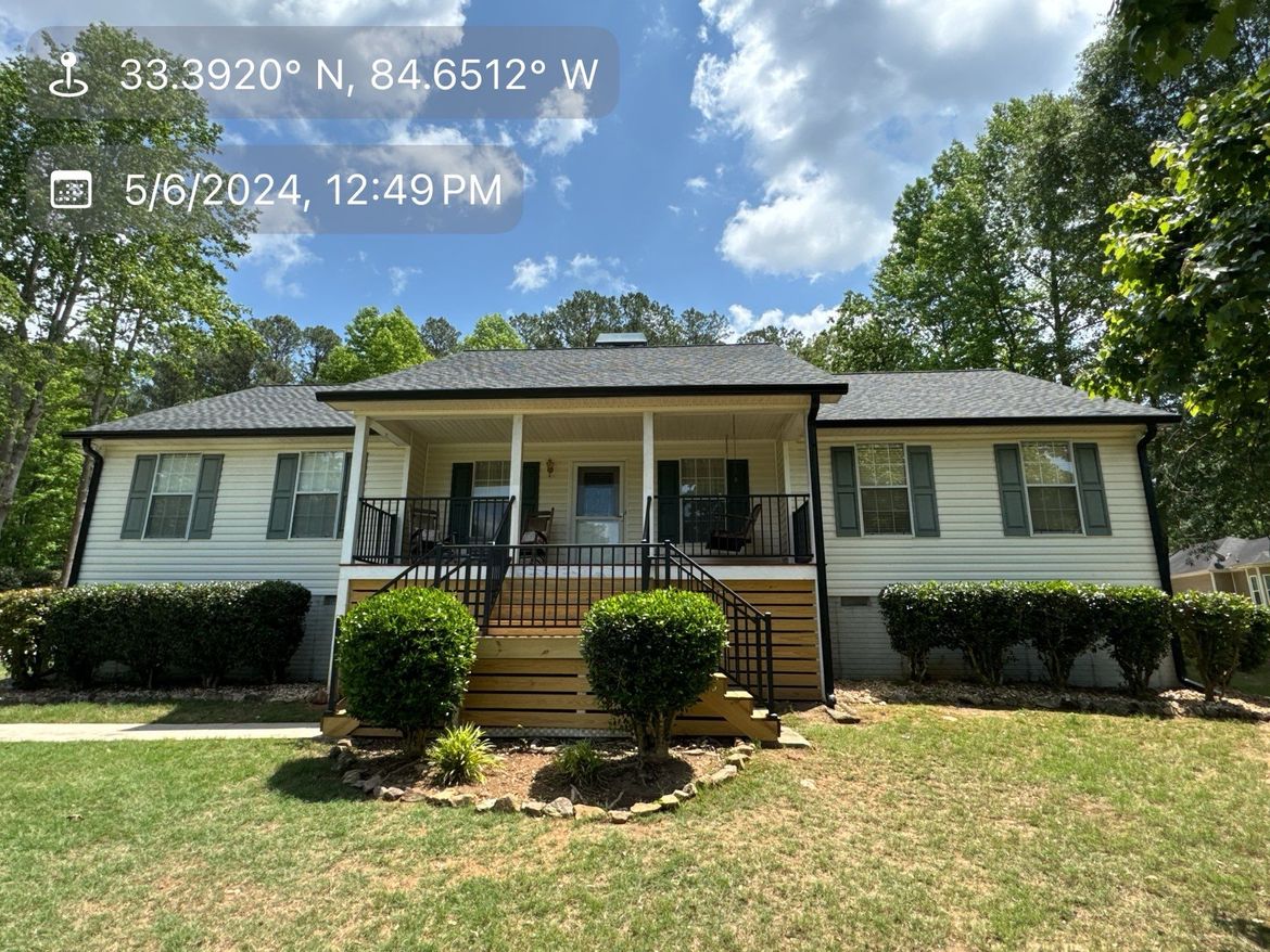 A white house with a gray roof and a porch