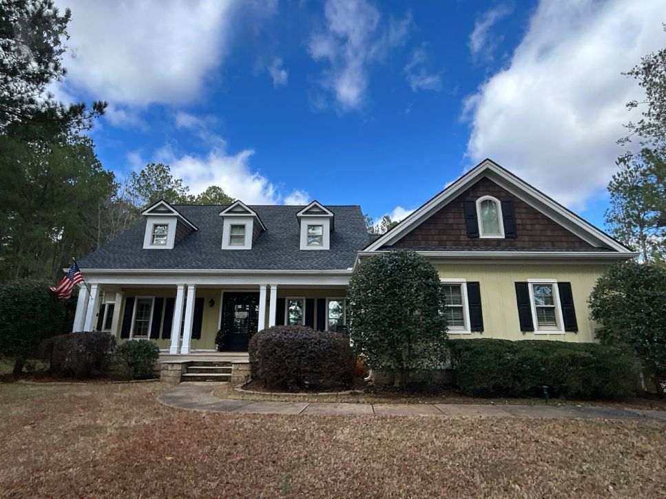 A large house with a blue sky and clouds in the background