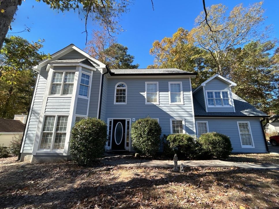 A large house with a lot of windows and bushes in front of it.