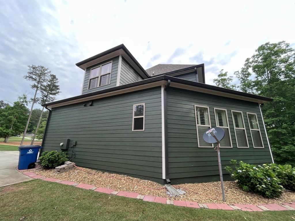 A green house with a satellite dish on the side of it.