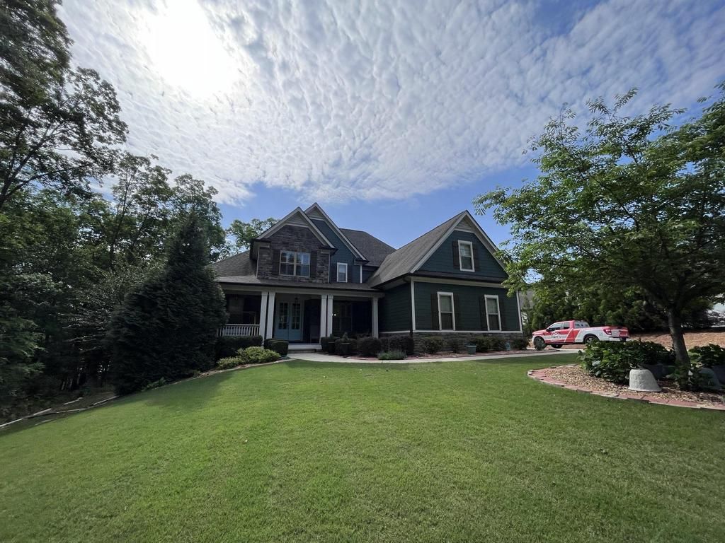 A large green house with a large lawn in front of it