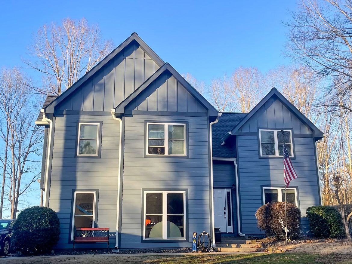 A large gray house with a picnic table in front of it