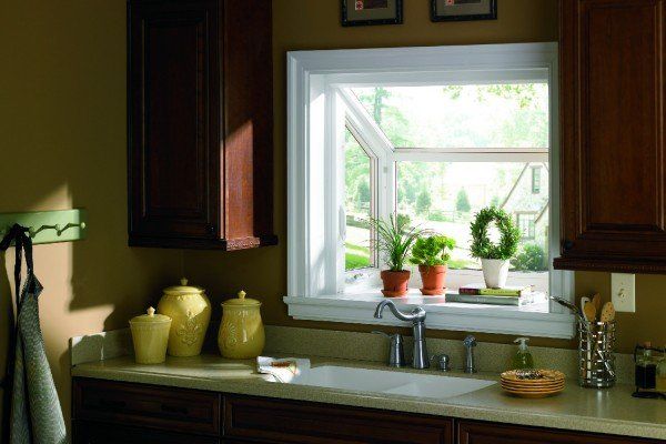 A kitchen with a sink and a window with potted plants on the window sill.