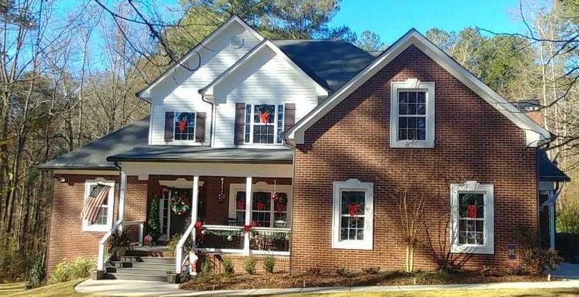 a large brick house with white trim and red wreaths on the windows