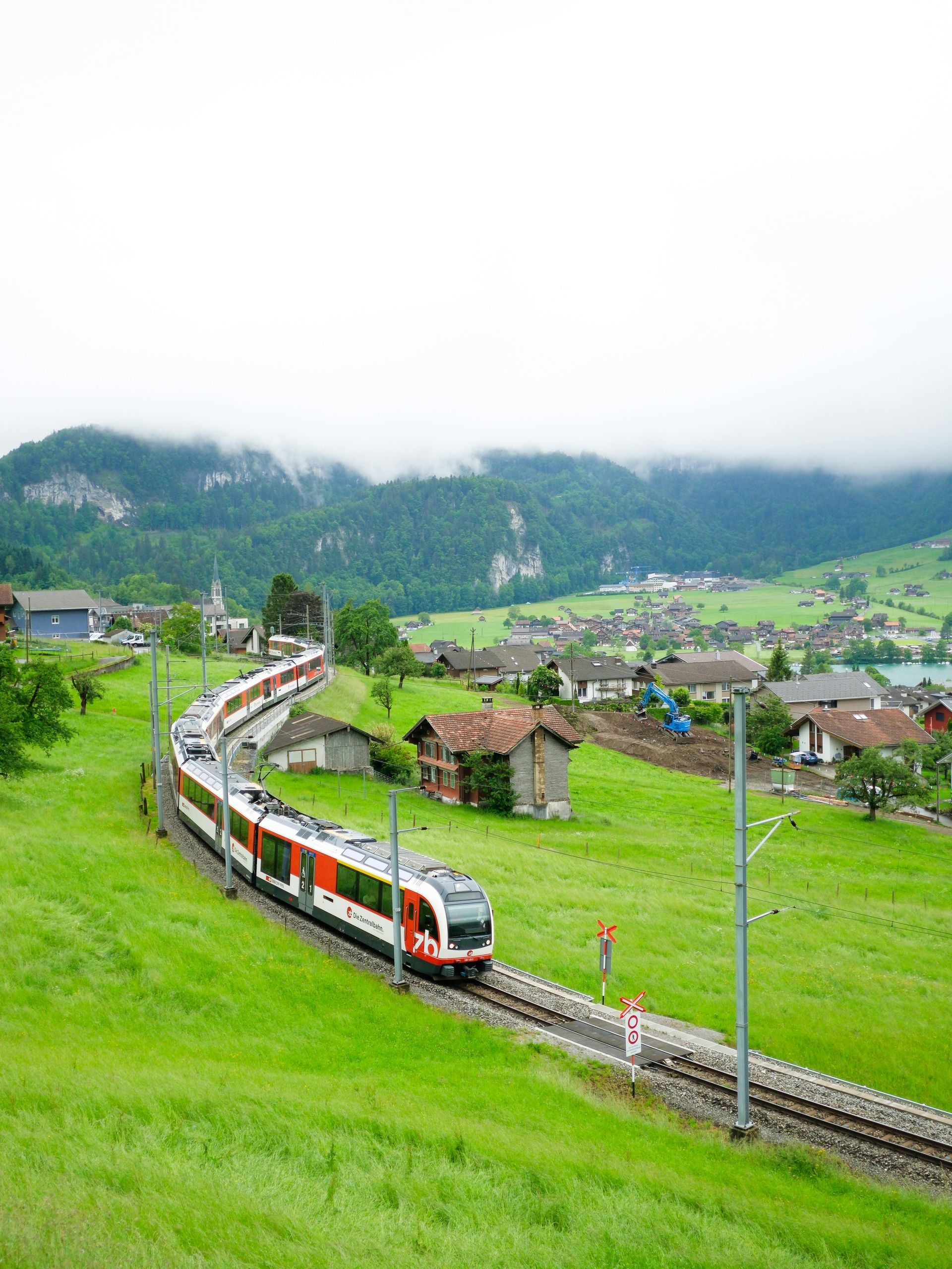A train is going down the tracks in the middle of a green field.