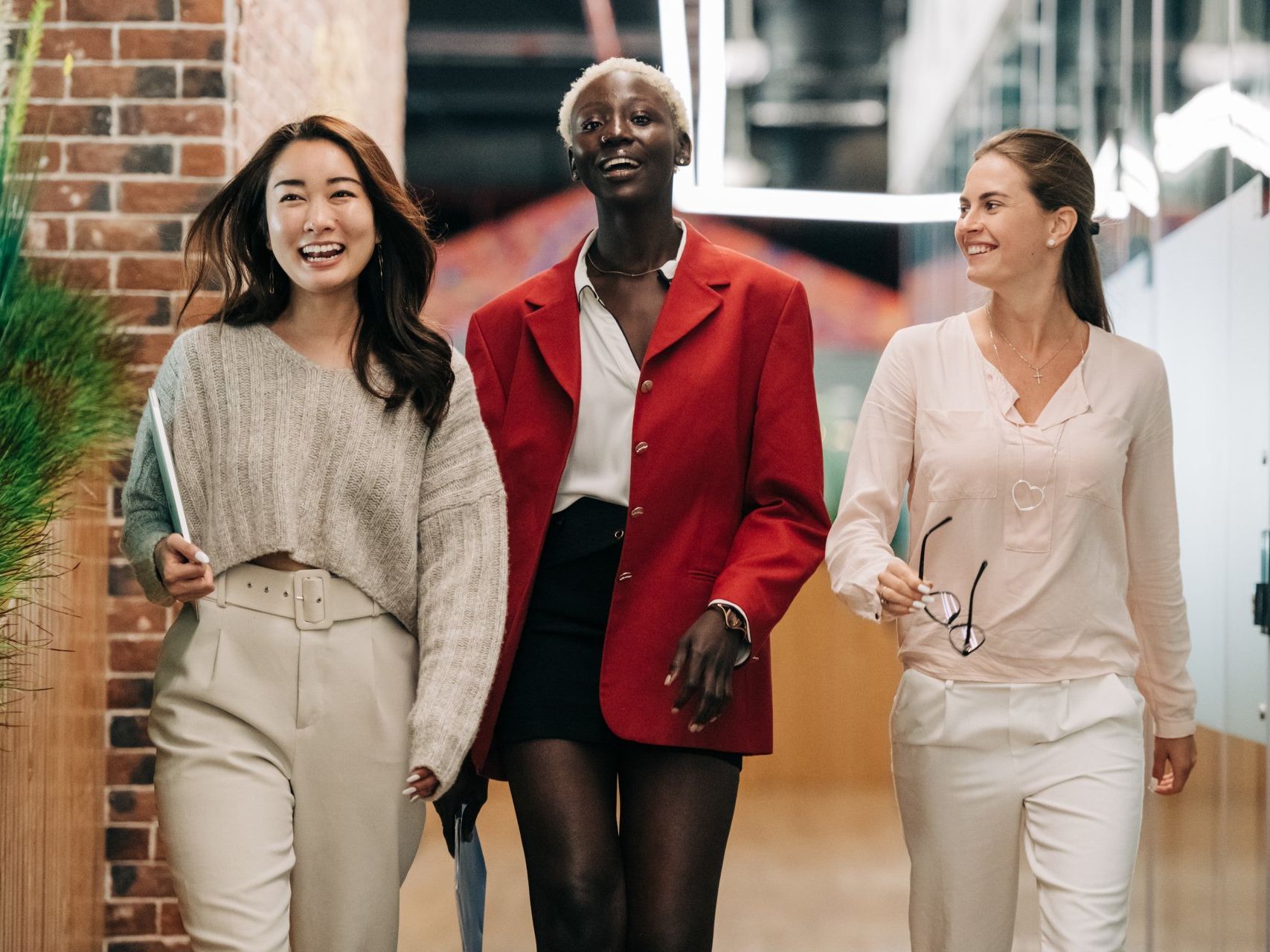 Three women are walking down a hallway together.