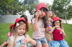 A group of young girls are blowing soap bubbles in a park.