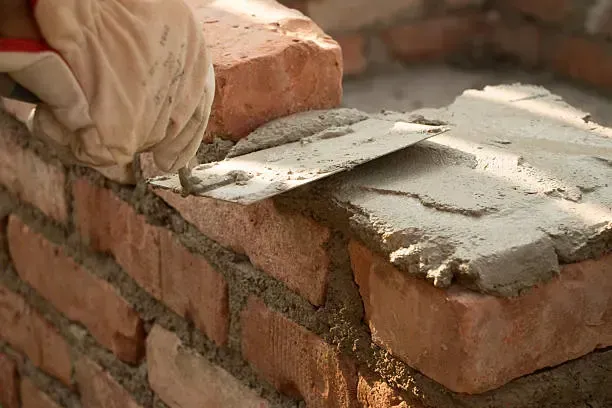A person is laying bricks on a wall with a trowel.