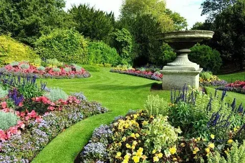 A garden with lots of flowers and a fountain in the middle