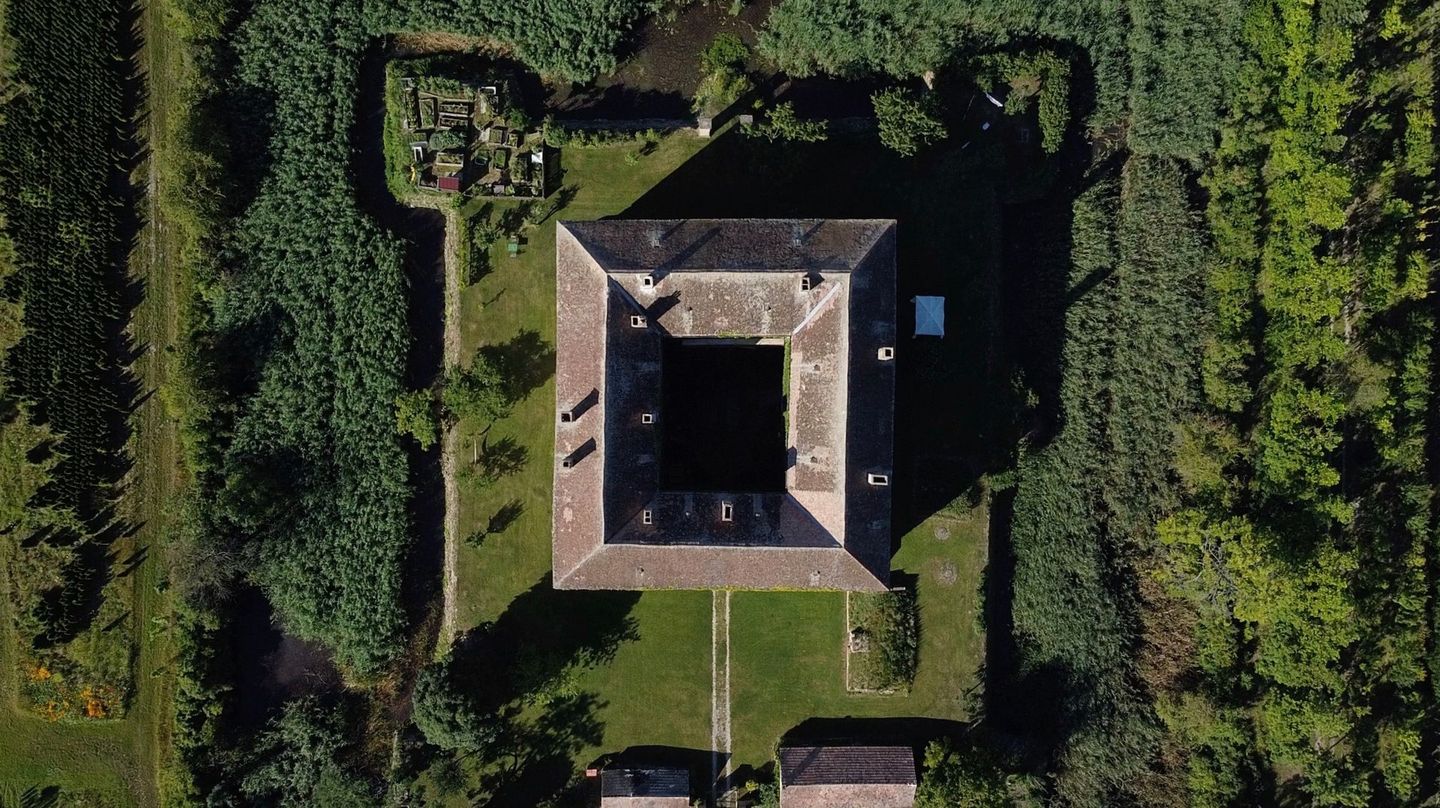 Schloss mit Burggraben von oben in grüner Landschaft