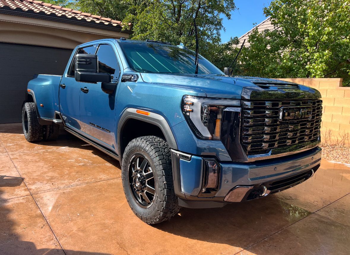 A blue pickup truck is parked in front of a garage.