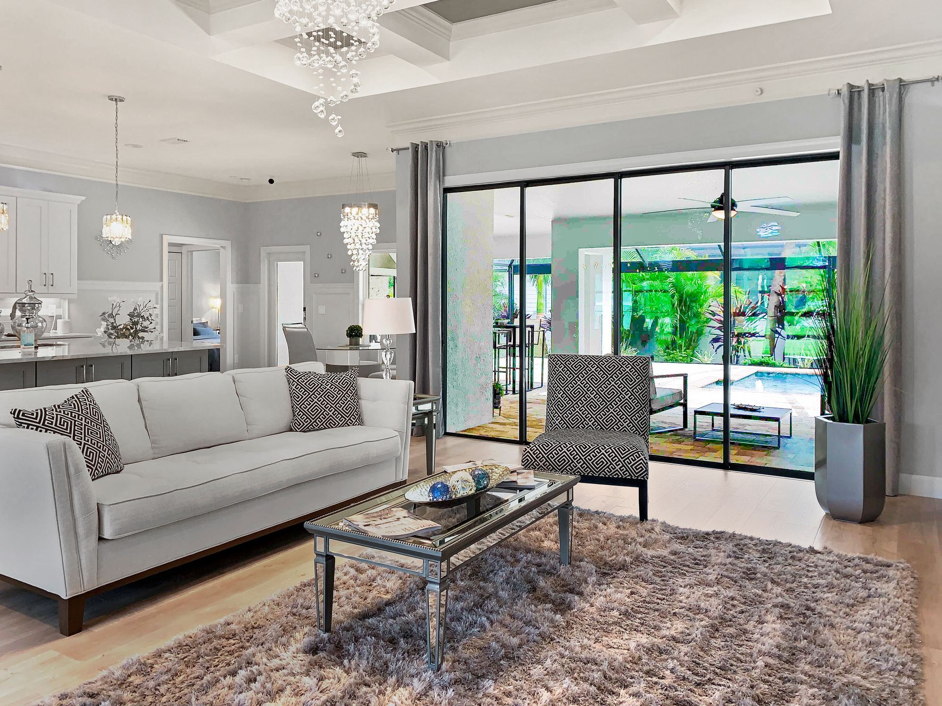 Living room with white sofa, patterned chair, rug, and glass doors overlooking a patio.