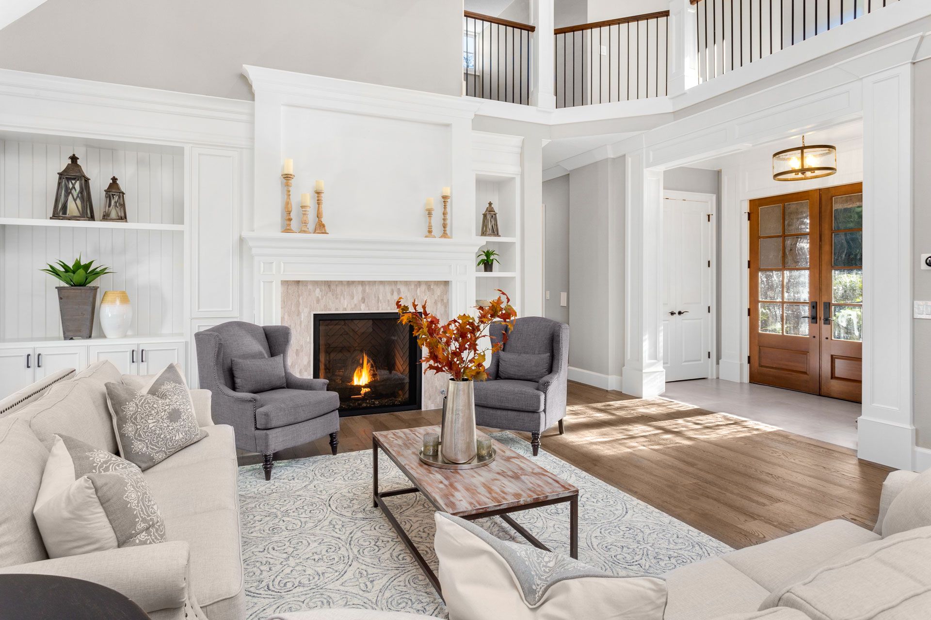 Elegant living room with fireplace, seating, and open entryway.