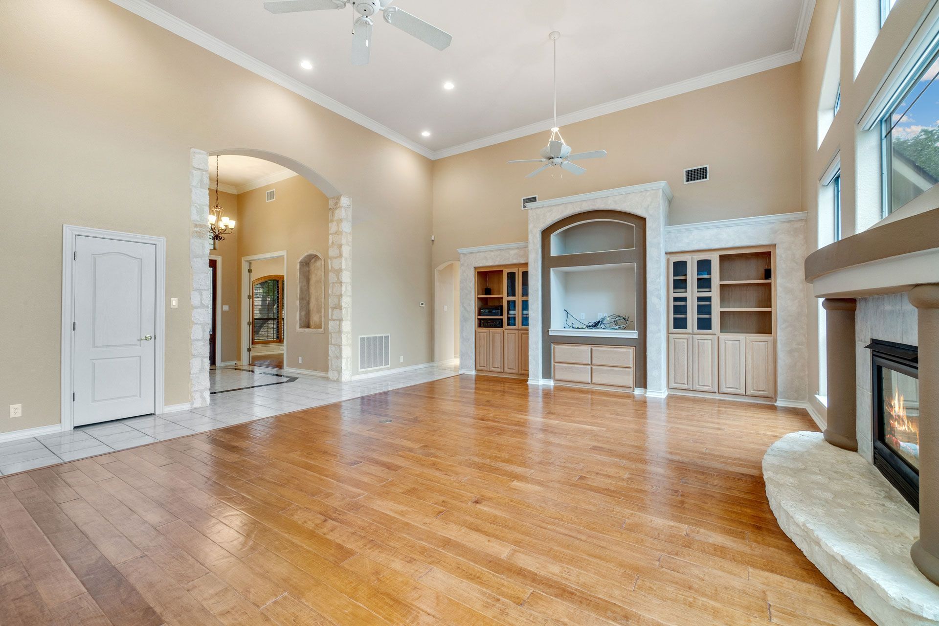 Spacious living room with high ceilings, hardwood floors, built-in shelving, and fireplace.